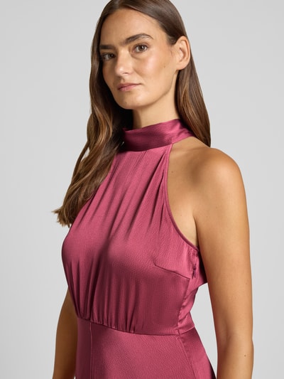 Vrouwenmodel draagt cocktailjurk met halter van Samsøe Samsøe in bordeaux, elastische materiaalmix, getailleerde pasvorm, midi-jurk, nahaufnahme bovenlichaam.