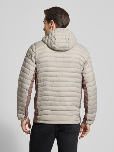 Männermodel trägt Steppjacke mit Kapuze und Logo van Columbia in beige met bruine accenten, regular fit, ruglengte maat M 72 cm, schouderbreedte 47 cm, borstwijdte 52 cm, mouwlengte 69 cm, ganzkörperansicht rückansicht.