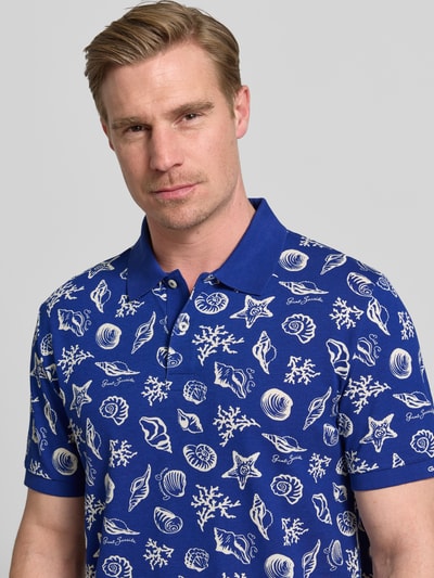 Männermodel trägt Regular Fit Poloshirt mit Allover-Motiv-Print von Gant in Blau und Weiß aus Reine Baumwolle, Nahaufnahme Oberkörper.
