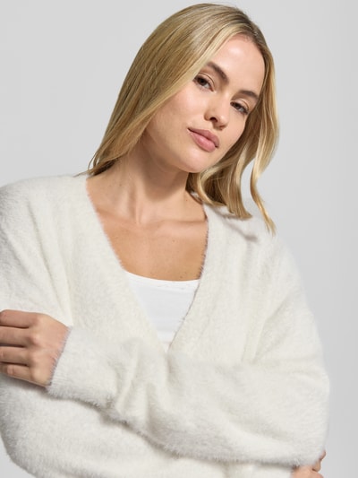 Vrouwenmodel draagt witte oversized Strickjacke mit durchgängiger Knopfleiste Modell 'BRULA' van ICHI, gebreide look, langem mouw, geribbelde boorden, detailopname bovenlichaam.