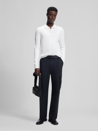Männermodel trägt Slim Fit Strick-Poloshirt aus Viskose-Mix Modell 'SAN PIPPO-CV' von HUGO in Weiß, feiner Rippstrick, Ganzkörperansicht von vorne.