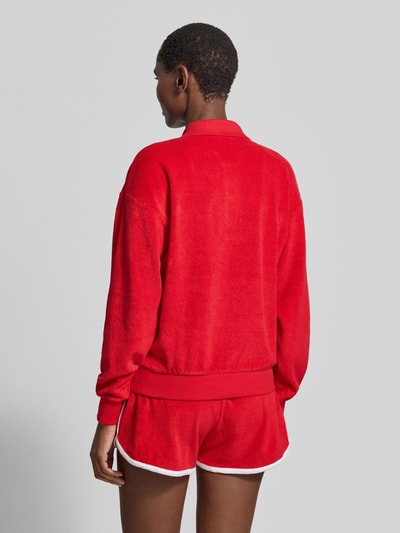 Frauenmodel trägt Regular Fit Poloshirt aus Baumwoll-Mix von Polo Ralph Lauren in Uni-Rot mit geripptem Abschluss und Brusttasche, Ganzkörperansicht Rückansicht.