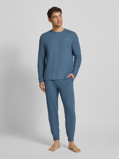 Męski model nosi Relaxed Fit Pyjama-Hose aus Baumwoll-Mix Modell 'AUSTIN PANTS' od HUGO, jednolity błękit, faktura waflowa, widok całej sylwetki z przodu.