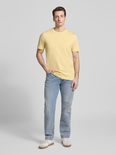 Męski model nosi T-Shirt mit Rundhalsausschnitt od Christian Berg Men, bawełna, krój regular fit, kolor jasny żółty, widok całej sylwetki z przodu. Długość tyłu w rozmiarze M: 70 cm.