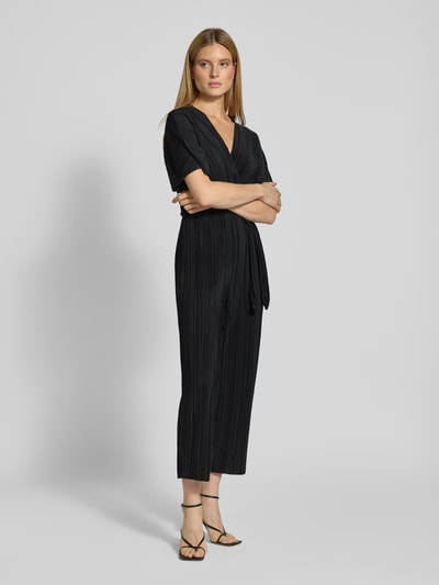 Vrouwenmodel draagt Regular fit jumpsuit met V-hals model 'Olinda' van YAS, geplisseerde look, korte mouwen, afneembare stoffen riem, zwarte kleur, taille-accent, enkelhoogte, voorkant volledig zichtbaar, volledig lichaamsperspectief.