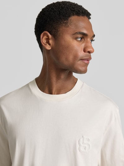 Männermodel trägt Regular Fit T-Shirt aus reiner Baumwolle Modell 'C-TAMES 03' von BOSS, Optik: Unifarben, Logo-Applikation, Nahaufnahme Oberkörper.