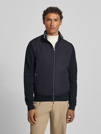Männermodel trägt Sweatjacke mit Stehkragen von bugatti aus Baumwoll-Mix, Regular-Fit, dunkle Farben, Reißverschlusstaschen, Label-Detail, Ganzkörperansicht von vorne.