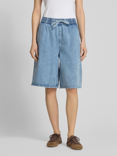 Frauenmodel trägt Jeansshorts mit weitem Bein Modell 'SIGNE' von Noisy May, reine Baumwolle, elastischer Bund, Ganzkörperansicht von vorne.