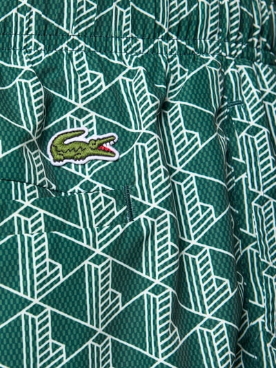 Produktfoto, Badehose mit Logo-Muster von Lacoste in Grün mit weißem Allover-Muster, appliziertem Logo und strukturierter Textur, Nahaufnahme.