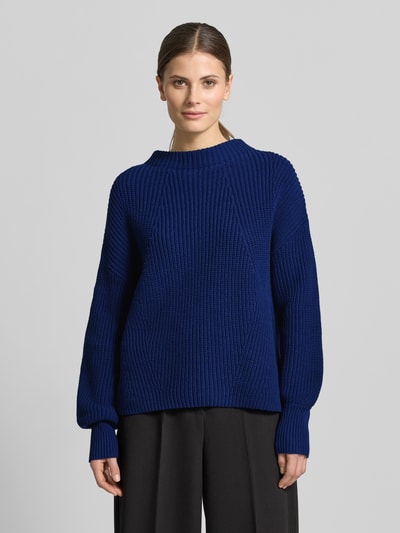Frauenmodel trägt Strickpullover mit Stehkragen Modell 'TELLINA' von Someday, lockerer Schnitt, dunkelblau, Baumwoll-Mix, gerippte Struktur, Ganzkörperansicht von vorne.