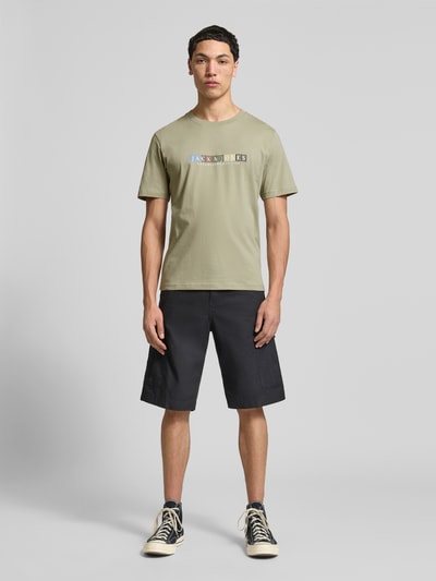 Männermodel trägt T-Shirt aus Bio-Baumwolle Modell 'NANTUCKET' von Jack & Jones in Hellgrün mit Label-Print, gerader Schnitt, Ganzkörperansicht von vorne.