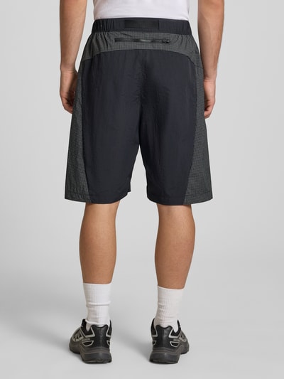 Männermodel trägt Shorts mit Logo und Gürtel von The North Face, dunkle Farben, elastischer Bund, Regular-Fit, Ganzkörperansicht Rückansicht.