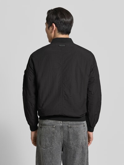Männermodel trägt schwarzen Blouson mit Label-Patches Modell 'IBE' von khujo, Gerader-Schnitt, Stehkragen, Rückenansicht, Struktur-Textur