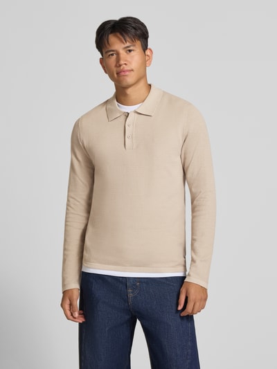 Männermodel trägt Slim Fit Poloshirt mit Label-Detail Modell 'AUSTIN' von JACK & JONES, beigefarbener Baumwoll-Mix mit Struktur-Muster, Langarm, Polokragen, Ganzkörperansicht von vorne.