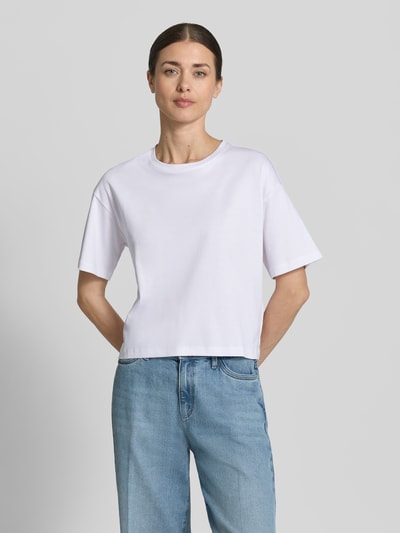 Kobiece model prezentuje damski t-shirt z bawełny, prosty krój, model 'Moa Melea' od MSCH Copenhagen, okrągły dekolt, biały, długość tyłu 50 cm w rozmiarze XS/S, widok całej sylwetki z przodu.