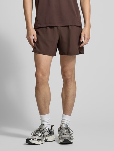 Männermodel trägt Shorts mit elastischem Bund und Eingrifftaschen von Salomon, regular fit, bruin, logo, vooraanzicht, detailopname benen