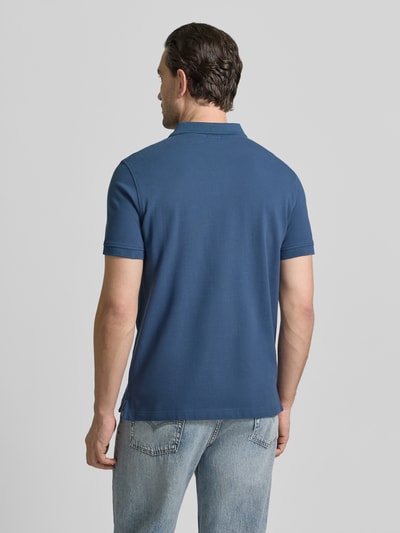 Männermodel trägt Slim Fit Poloshirt mit Logo-Stitching von MCNEAL in Blau, reine Baumwolle, Polokragen, Ganzkörperansicht Rückansicht.