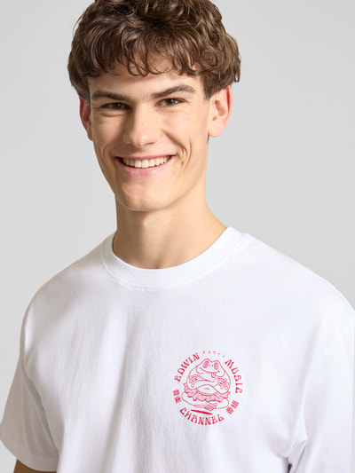 Männermodel trägt weißes T-Shirt aus reiner Baumwolle Modell 'MUSIC CHANNEL' von Edwin mit rotem Print, Nahaufnahme Oberkörper.