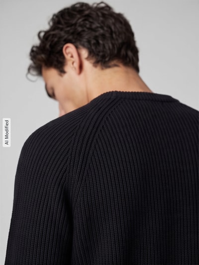 Männermodel trägt dunkelblauen, grob gestrickten Regular Fit Pullover aus reiner Baumwolle Modell 'BRAUN' von Selected, Nahaufnahme Rückansicht, Herren Pullover von Selected, KI-modifiziertes Bild.