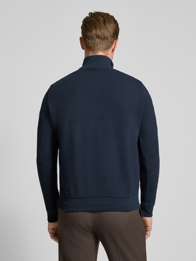 Männermodel trägt Sweatshirt mit Label-Details von bugatti in Dunkelblau, gerader Schnitt, strukturierter Stoff, Ganzkörperansicht Rückansicht. Elastischer Material-Mix mit Baumwoll-Anteil, Troyer-Kragen, Brusttasche, Rückenlänge 64 cm, Ärmellänge 66 cm.