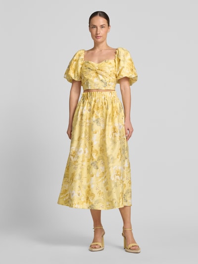 Frauenmodel trägt High Waist Midirock aus Lyocell-Mix Modell 'LEMON' von YAS, florales Muster, A-Linie, Drapierungen, Eingrifftasche, Ganzkörperansicht von vorne.