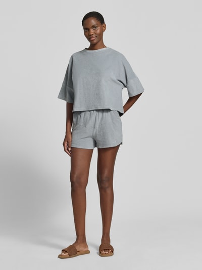 Frauenmodel trägt Relaxed Fit T-Shirt in Bouclé-Optik von Drykorn aus Reiner Baumwolle, Hellgrau, Halbarm, Rundhalsausschnitt, Ganzkörperansicht von vorne.