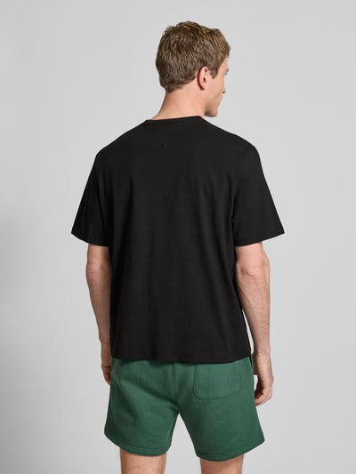 Männermodel trägt Regular Fit T-Shirt aus reiner Baumwolle von Tommy Jeans, Optik: Unifarben, Ganzkörperansicht Rückansicht.