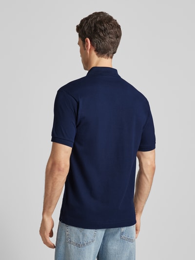 Männermodel trägt Poloshirt mit Label-Stitching Modell 'L.12.12 CORE' von LACOSTE in Unifarben, reine Baumwolle, Regular Fit, Rückenlänge 72 cm, Ganzkörperansicht Rückansicht.