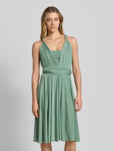 Frauenmodel trägt Knielanges Cocktailkleid mit tiefem V-Ausschnitt von Rose Avenue, Taillierter Schnitt, Taillenband, Knielänge, Ganzkörperansicht von vorne.