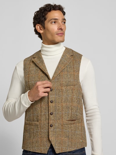 Männermodel trägt Weste aus Schurwolle mit Brustleistentasche Modell 'Warner' von Carl Gross in Beige mit Fischgrätmuster, Nahaufnahme Oberkörper. Reine Schurwolle, Regular Fit, Reverskragen, Knopfleiste, seitliche Leistentaschen, neutrale Farbtöne, feine Textur.