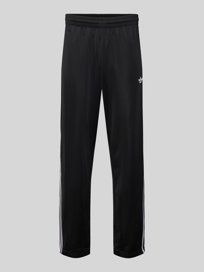 Produktfoto, Sweatpants mit elastischem Bund von adidas Originals in Schwarz mit weißen Details, locker geschnitten, Label-Stitching, Reißverschlusstaschen.