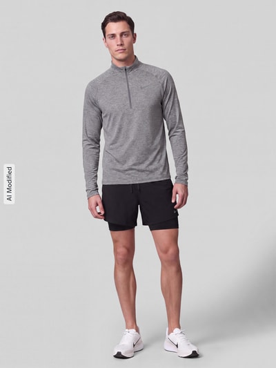 Mężczyzna prezentuje bluzkę z długim rękawem Regular Fit Sport-Langarmshirt mit Troyer-Kragen von Nike w kolorze szarym, jednolita faktura, Ganzkörperansicht von vorne, KI-modifiziertes Bild. Kontext: Herren Sport-Langarmshirt von Nike Training.