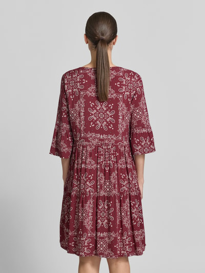 Frauenmodel trägt Relaxed Fit Minikleid aus reiner Viskose von Christian Berg Woman Selection mit Allover-Paisley-Print, Tunika-Ausschnitt und 3/4-Arm, Rückenlänge bei Größe 36: 89 cm, Brustweite: 49 cm, Ärmellänge: 39 cm, Bordeauxrot mit weißem Muster, lockere Form, fließende Textur, Ganzkörperansicht Rückansicht.