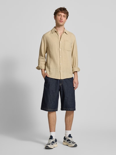 Männermodel trägt Slim Fit Freizeithemd aus Leinen-Baumwoll-Mix Modell 'NELSON' von Redefined Rebel, beige, Kentkragen, Brusttasche, Label-Detail, Ganzkörperansicht von vorne, Kontext: Rückenlänge bei Größe M 50 cm, Schulterbreite 49 cm, Ärmellänge 72 cm.