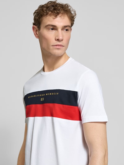Männermodel trägt Regular Fit T-Shirt mit Rundhalsausschnitt von Christian Berg Men, Statement-Print in Weiß, Rot und Schwarz, Nahaufnahme Oberkörper.