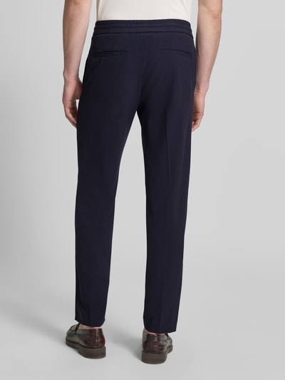 Mężczyzna nosi Relaxed Fit Sweatpants mit Viskose-Anteil von Lindbergh, elastyczna mieszanka materiałów z dodatkiem wiskozy, kanty, krój relaxed fit, tunel, szerokość w rozmiarze M: 41 cm, długość wewnętrzna nogawki w rozmiarze M: 79 cm, ciemnogranatowe, gładka tekstura, widok całej sylwetki od tyłu
