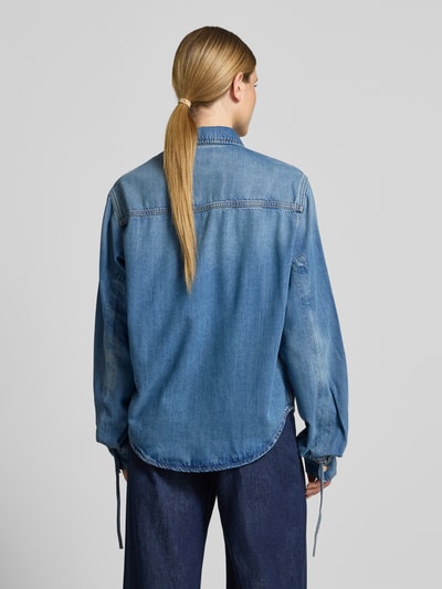 Frauenmodel trägt Oversized Jeansbluse aus Lyocell-Baumwoll-Mix Modell 'JUZY' von Essentiel Antwerp in mittelblau, Ganzkörperansicht Rückansicht.