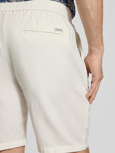 Männermodel trägt Shorts aus Baumwoll-Leinen-Mix Modell 'FAVE' von Scotch & Soda in Regular Fit, cremefarben, elastischer Bund, Detailaufnahme Rückansicht. Kontext: Herren Shorts, Bundweite 42 cm, Innenbeinlänge 21 cm bei Größe 32.