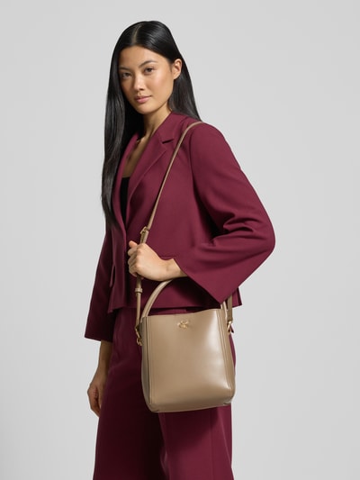 Kobiece modelka nosi torebkę z uchwytem Handtasche mit Tragehenkel od CK Calvin Klein, mieszanka materiałów, detal z logo, główna przegroda z zamkiem błyskawicznym, pasek na ramię, szerokość 22 cm, długość 22 cm, głębokość 14 cm, długość paska 122 cm; widok całej sylwetki z przodu.