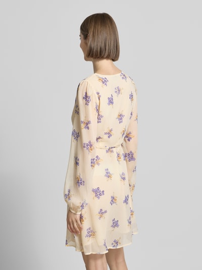 Frauenmodel trägt Minikleid aus Chiffon Modell 'MIRIAM-FUSINA' von Only mit florales-Allover-Muster, Taillengürtel, Ballonärmel und Knopf, zartes Gelb mit lila Blumen, transparent wirkende, leicht fließende Textur, Mini-Länge, Rückansicht.