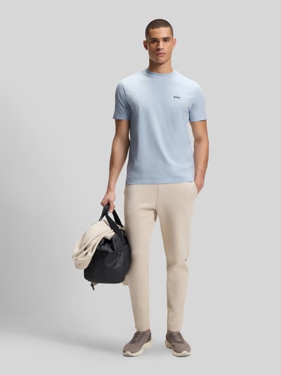Männermodel trägt Regular Fit T-Shirt aus Baumwoll-Mix Modell 'TEE' von BOSS Green in Optik: Unifarben mit Label-Print, Rundhals, Kurzarm, Ganzkörperansicht von vorne.