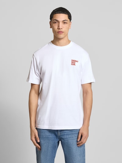 Männermodel trägt weißes Relaxed Fit T-Shirt aus reiner Bio-Baumwolle Modell 'FRED' von Only & Sons mit rotem Print, Ganzkörperansicht von vorne.