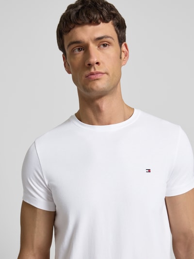 Männermodel trägt Slim Fit T-Shirt mit Rundhalsausschnitt von Tommy Hilfiger aus Baumwoll-Elasthan-Mix mit Logo-Stickerei, Nahaufnahme Oberkörper.