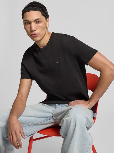 Männermodel trägt Regular Fit T-Shirt aus reiner Baumwolle von Tommy Jeans, Optik: unifarben, Logo-Detail, Rundhals, Kurzarm, Jersey; Nahaufnahme Oberkörper.