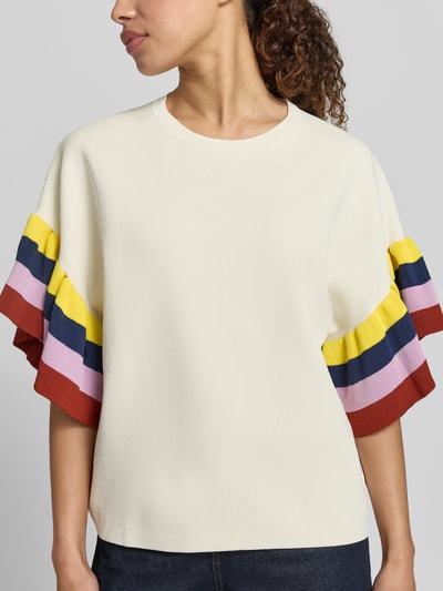 Frauenmodel trägt Boxy Fit Pullover aus Viskose-Mix Modell 'JANUARY' von Essentiel Antwerp, cremefarben mit bunten Streifenärmeln, Nahaufnahme Oberkörper.