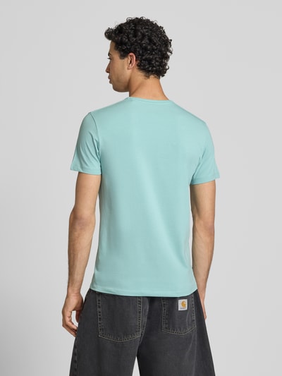 Męski model nosi Slim Fit T-Shirt aus Baumwoll-Mix Modell 'ORIGINAL BASIC 3N' von Pepe Jeans, krój slim fit, jednokolorowy, mieszanka bawełny, okrągły dekolt, krótki rękaw, nadruk z logo, dżersej; Ganzkörperansicht Rückansicht.