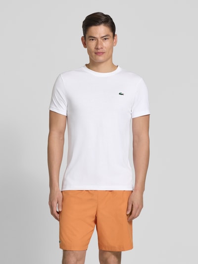Männermodel trägt Regular Fit T-Shirt aus Baumwoll-Mix von Lacoste in Optik: Unifarben mit Logo-Patch und Rundhals, Ganzkörperansicht von vorne.