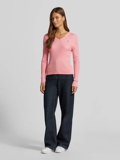 Vrouwenmodel draagt Regular Fit Pullover uit puur katoen van Tommy Hilfiger in lichtroze, gestructureerd breisel, donkere jeans, volledige vooraanzicht. Dames Pullover