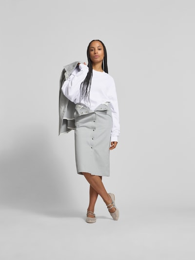 Frauenmodel trägt Oversized Longsleeve aus Baumwolle von black palms in Weiß mit Rundhalsausschnitt und elastischen Ärmelabschlüssen, Oversized-Schnitt, Rückenlänge bei Größe S: 79 cm, Ganzkörperansicht von vorne.