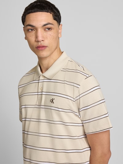Männermodel trägt Regular Fit Poloshirt mit Logo-Stitching von Calvin Klein Jeans, beige mit braunen Streifen, Reine Baumwolle, Nahaufnahme Oberkörper.